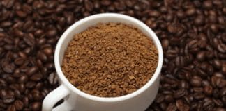 Café solúvel em xícara com grãos de café ao redor