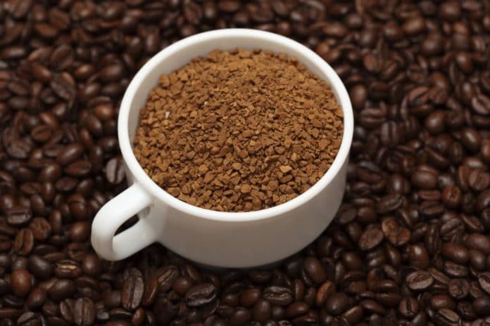 Café solúvel em xícara com grãos de café ao redor